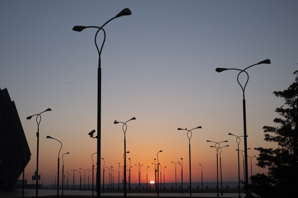 Rua com vários postes de energia instalados.