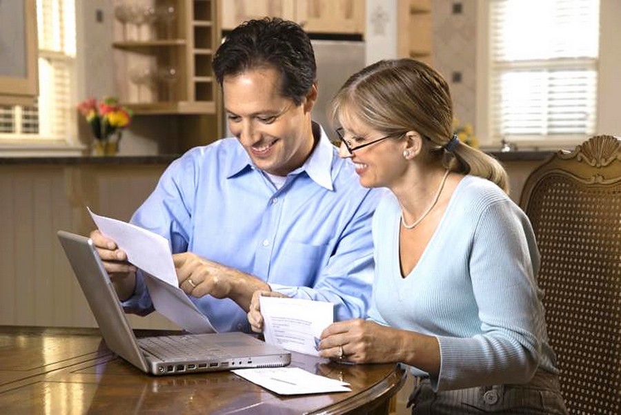 Couple paying bills online with laptop computer at home.